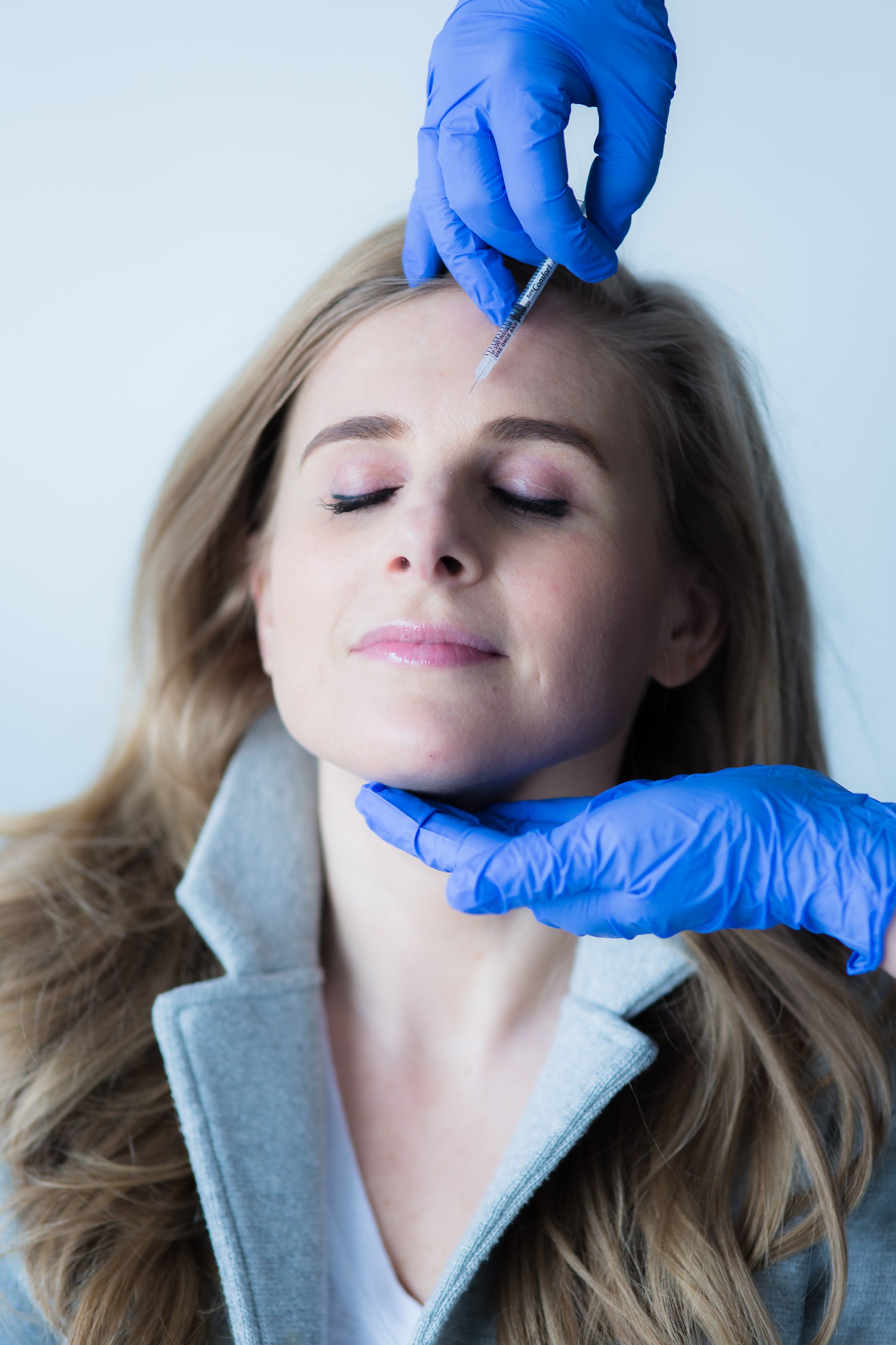A gloved injector administering a precise cosmetic injection to a calm client